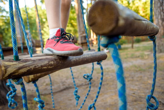 Boy foot shoe close up in adventure climbing high wire park - people on course in mountain helmet and safety equipment