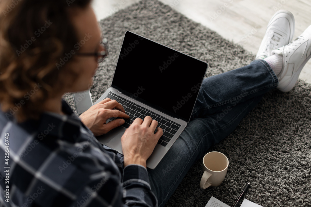 Poster back-view of guy using laptop with blank screen sitting indoor