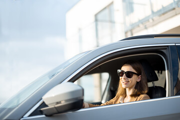 Naklejka premium Young woman in sunglasses left the house and driving a car. Businesswoman going to work from the house.