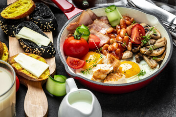 English breakfast with fried eggs, bacon, mushrooms, chicken fillet, beans, toasts and fresh salad. Food recipe background. Close up