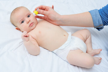 loving mother instills baby nasal drops into her son's nose.