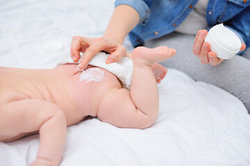 mother's hand applies a moisturizing baby cream to the baby boy's skin. Hygiene of the newborn...