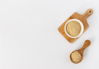 Dry yeast in a bowl and wooden spoon on a white background. Horizontal orientation, top view, copy space.