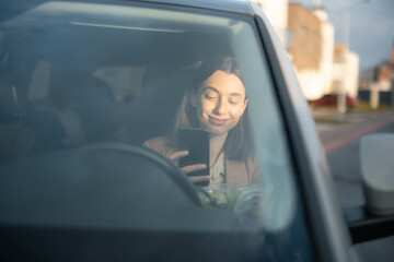 Young woman in sunglasses talking on the phone and driving a car. Businesswoman going to work from the house.