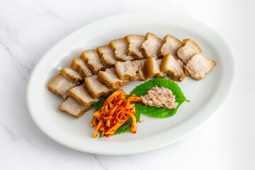 Bossam, boiled pork is eaten with spicy radish and Salted shrimp