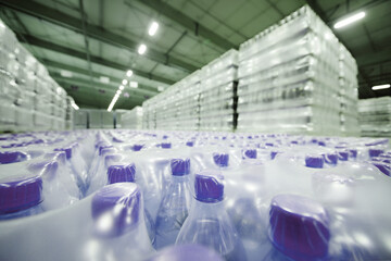 a huge industrial warehouse with plastic food wrap wrapped plastic bottles with carbonated drinks,  water or beer.