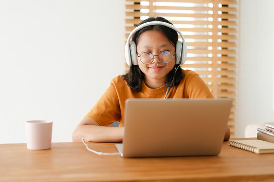 Asian student woman learning online using a computer laptop with headphones 
