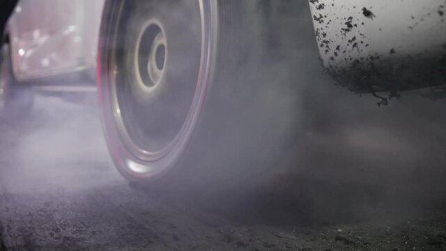 Drag racing car burning tire at starting line in race  track