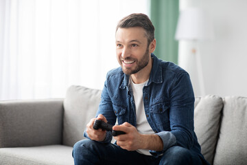 Joyful middle-aged man playing video games at home - Powered by Adobe