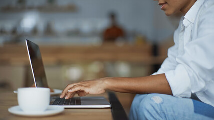 partial view of african american woman using laptop in cafe