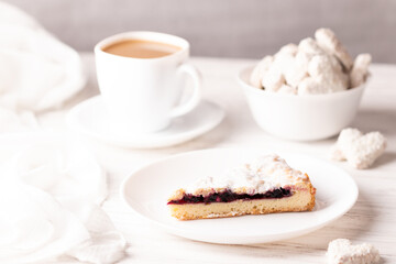 Vegan pie stuffed with cherries. Prepared without milk or eggs. In the background, a coffee with almond milk and vegan heart-shaped cookies. Photograph of breakfast in white colors