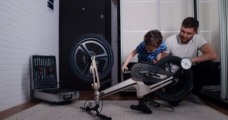 The father and the child, the son, play and repair the bicycle at home