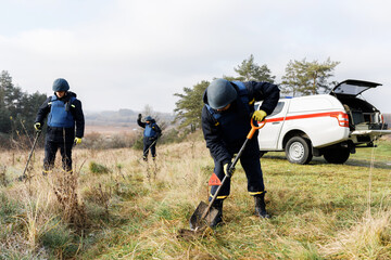 Men work in emergencies. Emergency workers work outdoors. A man in uniform works with a metal detector