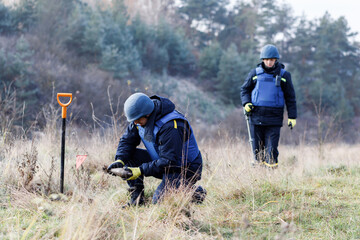 A man in a special suit works with a detector and found an explosive device. Dangerous work © nazariykarkhut
