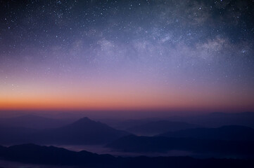 Beautiful picture of the night sky seen from the mountain peak, overlapping mountains, sea of mist, constellations and the Milky Way.