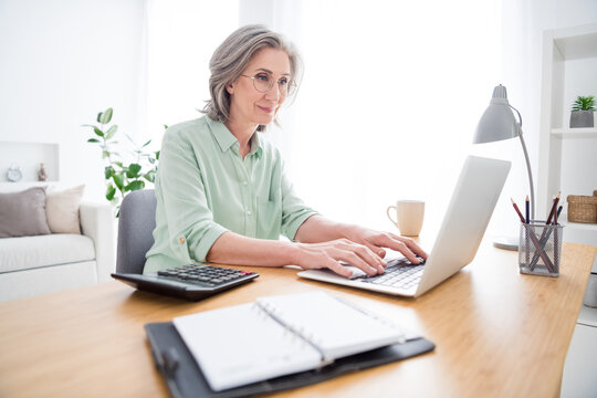 Profile photo of charming person sit behind desk look use laptop typing email working from home indoors