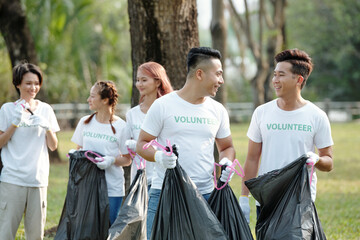 Young men and women picking up trash when cleaning city park