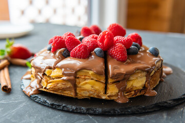 Pancakes with dessert filling and berries on a dark background.