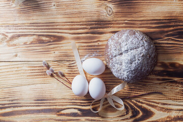 Easter composition in a simple style with white eggs, rye bread, a willow branch on a natural wooden background