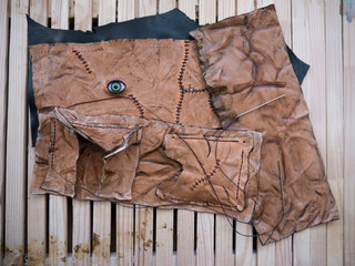 Leather pouch made of fresh zombie skin with green bloody eye and scars stitched with dark brown...