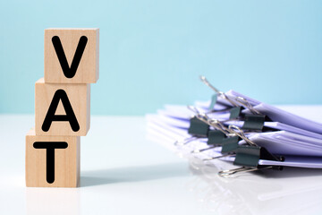 Vat on wooden cubes and stack of papers. financial concept background