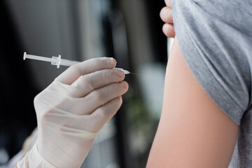 Cropped view of doctor holding syringe near patient during vaccination