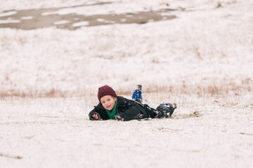 Fototapeta na wymiar Happy boy having fun playing outdoors in winter. Winter holidays and vacations. The boy is lying in the snow.
