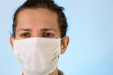 An adult male dressed in a white lab coat with a protective face mask on. Ready to work in a clean room or laboratory