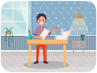 Man creates origami with scissors and paper in his hands. Guy sits near table with paper bird