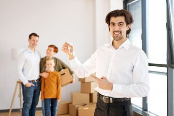 Fototapeta premium Handsome Smiling Cheerful Real Estate Agent In Formal Wear Holding Keys In Hands Posing At Camera
