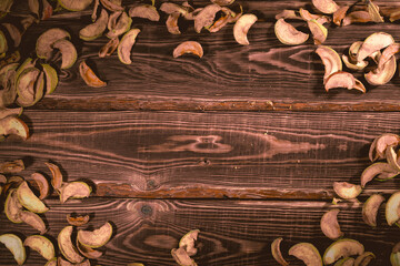 Slices of dried apples on a wooden background.
