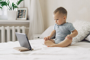 Little Boy sitting with a tablet in the room. The boy watching cartoons on the tablet. Technology concept.