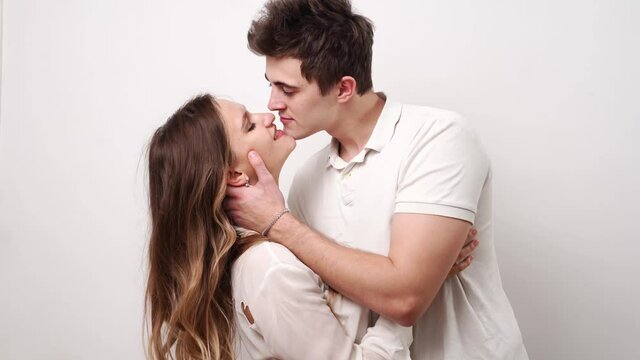 love, passionate and beautiful couple kisses against the white wall. 