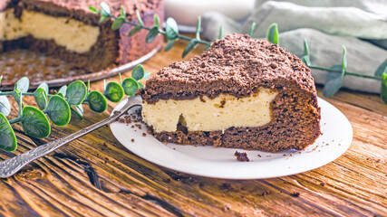 A piece of homemade chocolate pie with curd filling on a plate on a wooden table, close-up