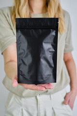 Kraft black paper packaging in a woman hands. Packaging for coffee, cosmetics. Packing closeup. Product for sale. Online shopping. Boxes with surprise. Delivery service, shipping. Empty, mockup