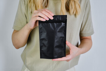 Kraft black paper packaging in a woman hands. Packaging for coffee, cosmetics. Packing closeup....