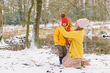 Mother putting hat on her son. Background winter forest