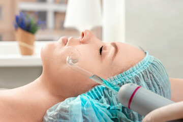 The beautician cleans the skin of the girl's Darsonval cosmetology apparatus. Facial hygiene,...