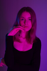 Girl portrait in neon light. Young slim woman model in black dress