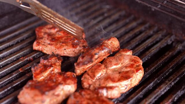 Fleisch wird mit der Grillgabel auf dem Griller gewendet und anger&ouml;stet und gebraten