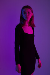 Girl portrait in neon light. Young slim woman model in black dress