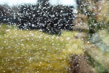 Dirty glass of kitchen window with stains and dust, view from the interior out on the garden - blurred background. It's high time to clean the window