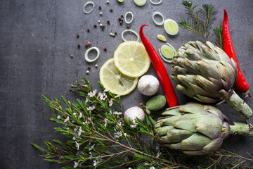 Fresh seasonal vegetables on a table. Top view photo of lime slices, artichoke flowers, garlic, leeks and cherry tomatoes. Eating fresh concept. 