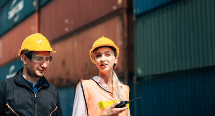 workers teamwork man and woman in safety jumpsuit workwear with yellow helmet  talking at cargo container shipping warehouse. transportation import,export logistic industrial service