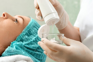 The beautician is putting cream on the face mask. The concept of facial hygiene, cosmetic...