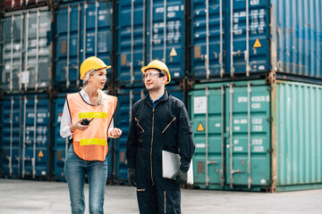 workers teamwork man and woman in safety jumpsuit workwear with yellow helmet use laptop and talking at cargo container shipping warehouse. transportation import,export logistic industrial service