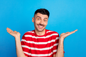 Naklejka premium Photo of funny puzzled young man wear striped t-shirt rising arms isolated blue color background