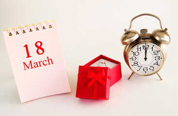 calendar date on light background with red gift box with ring and alarm clock with copy space. March 18 is the eighteenth day of the month