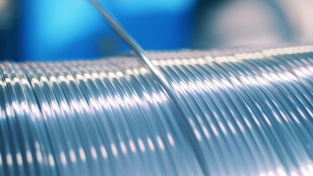 Shiny silver electrical wire unwinding from a spool