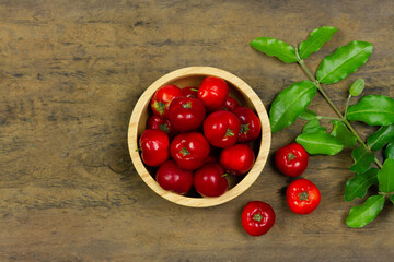 Acerola Cherry or Barbados Cherry with leaf in wooden bowl on wooden background, Top view.